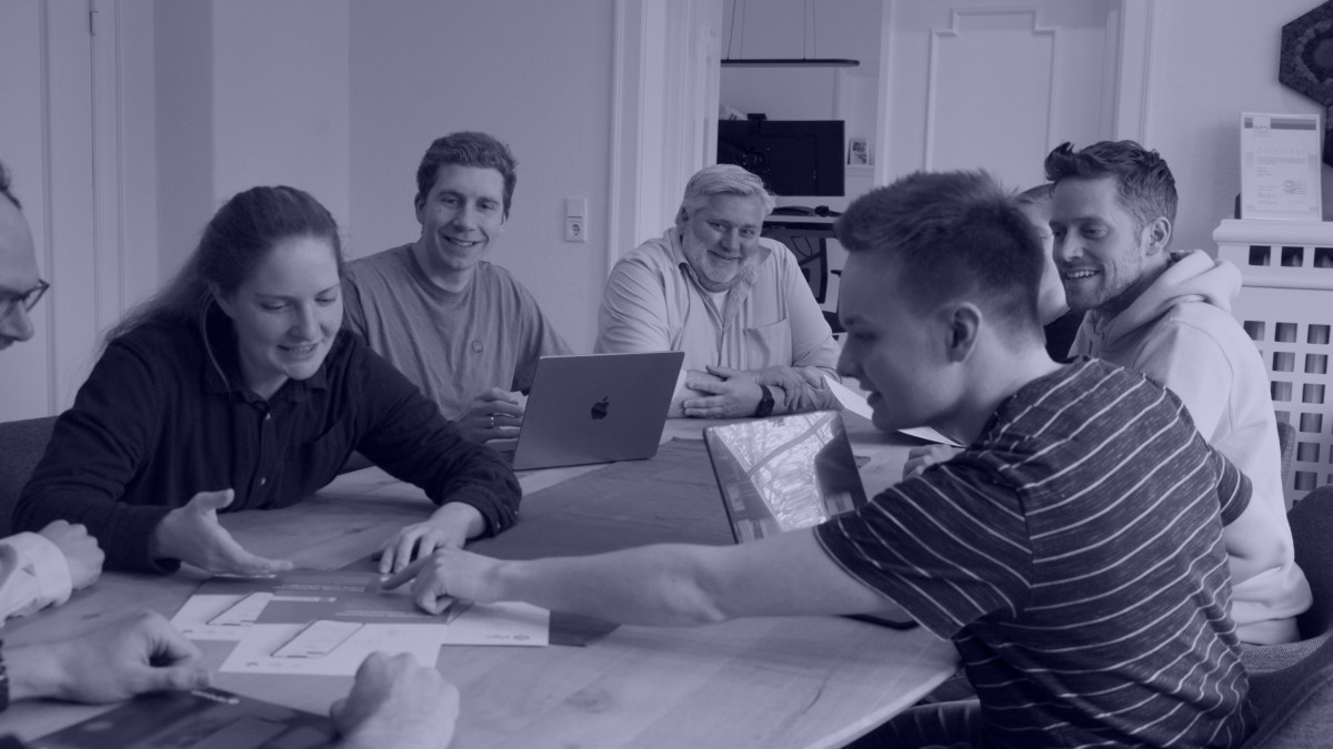 Team bespricht ausgedruckte App-Entwürfe am Besprechungstisch