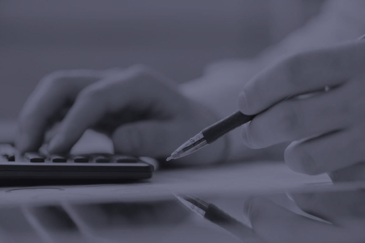 Jemand hält einen Stift in der Hand und bedient einen Taschenrechner.